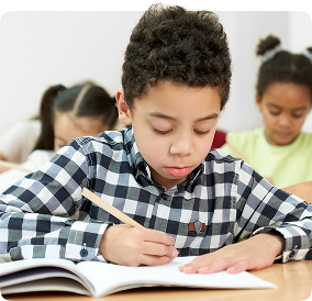 Estudante concentrado escrevendo em sala de aula com materiais didáticos da Amplia Plataforma de Ensino.