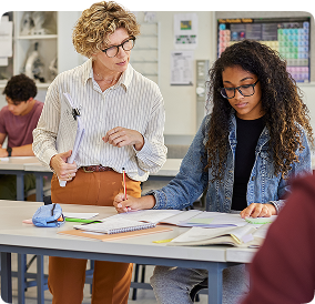 Professora orientando aluna durante atividade em sala, utilizando metodologias apoiadas pela Amplia Plataforma de Ensino.