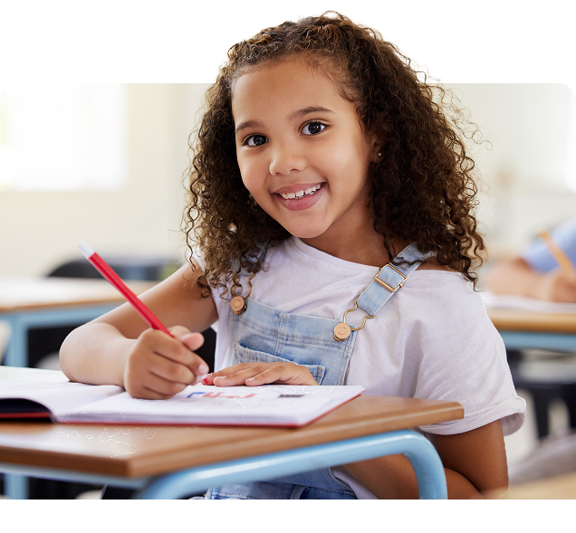 Estudante sorrindo enquanto escreve em sala de aula, em ambiente apoiado pela Amplia Plataforma de Ensino.