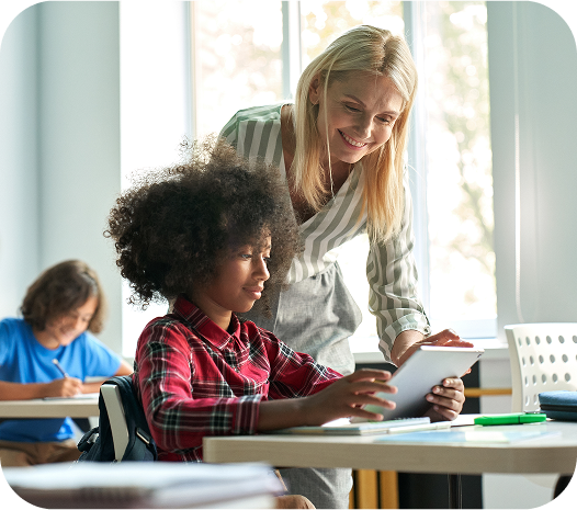 Professora orientando aluno em atividade com tablet, utilizando recursos digitais oferecidos pela Amplia Plataforma de Ensino.