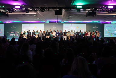 Palestrantes e público participando de apresentação no evento Conexão Amplia 2025, realizado pela Amplia Plataforma de Ensino.