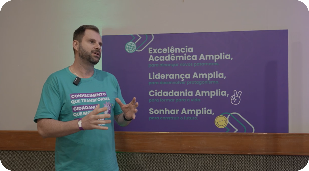 Educador apresentando palestra em evento da Amplia Plataforma de Ensino sobre excelência acadêmica, liderança e cidadania.