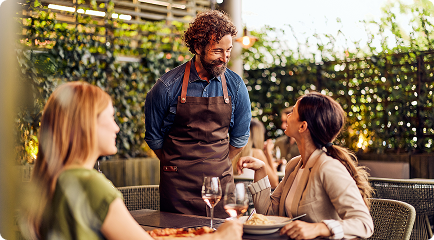 Cliente em ambiente externo de restaurante vivendo experiência gastronômica com atendimento personalizado.