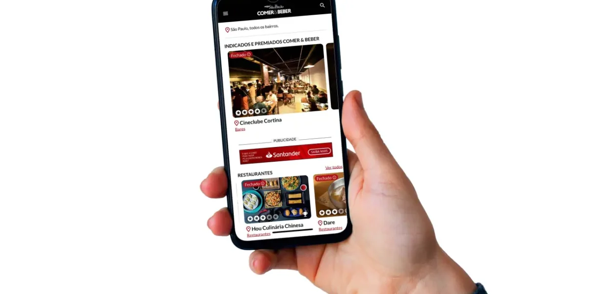 Mão segurando aparelho de celular com imagem de página do site da Veja Comer e Beber.
