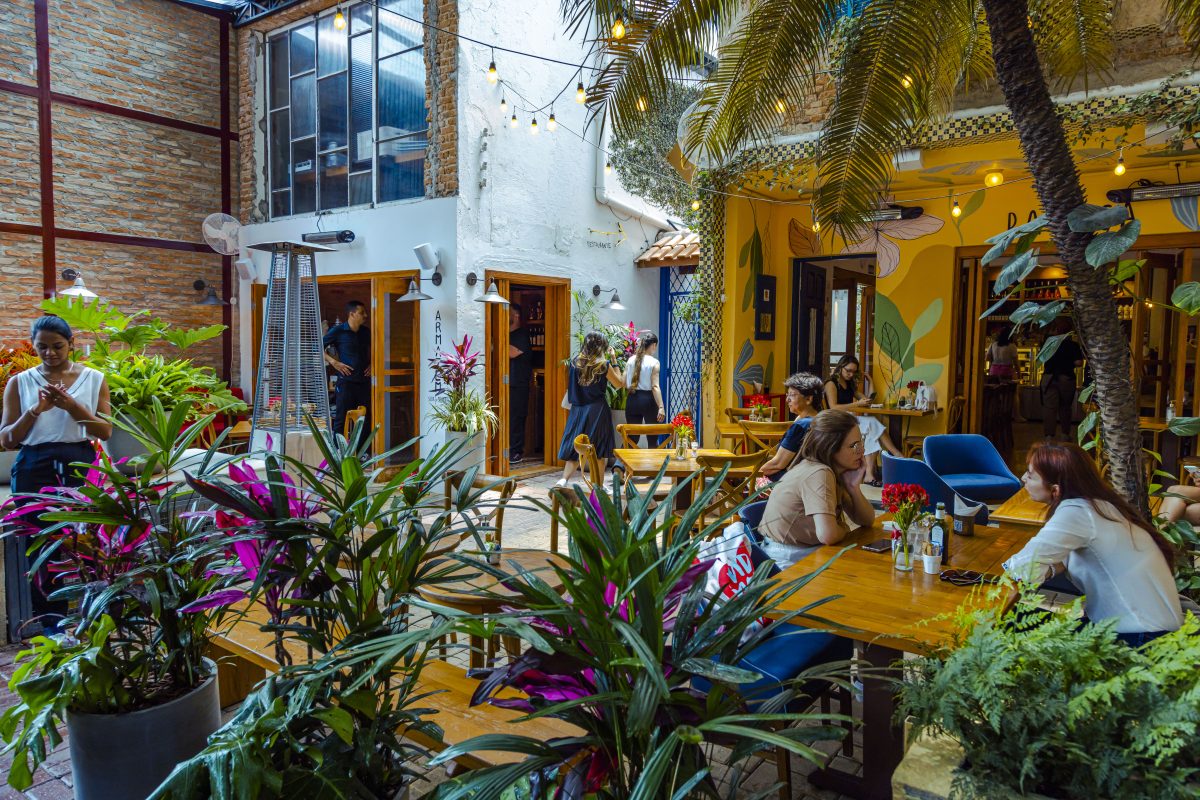 Imagem do ambiente do restaurante Gael Cozinha Mestiça com mesas e pessoas sentadas e um garçom.