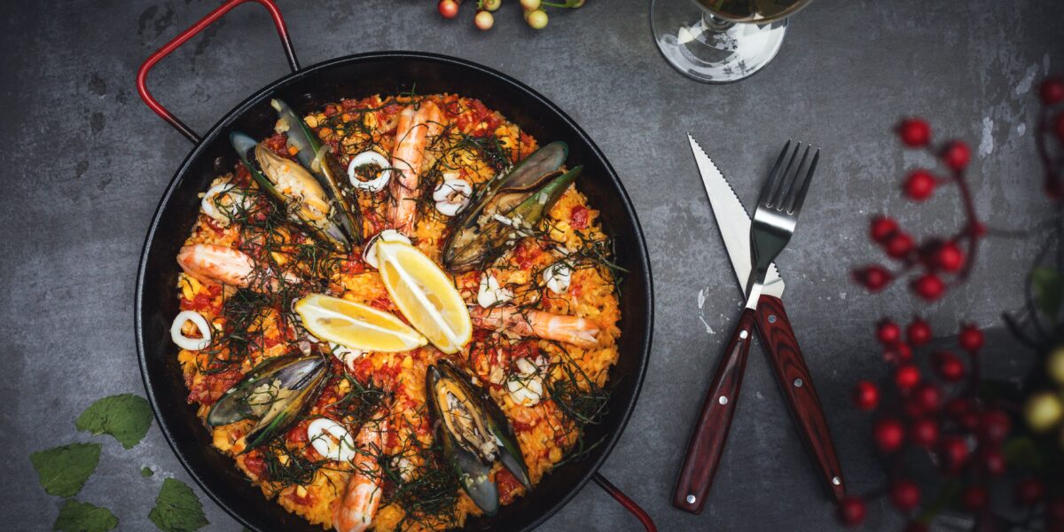 Prato de Paella, tradicional prato da culinária espanhola, com talher ao lado.
