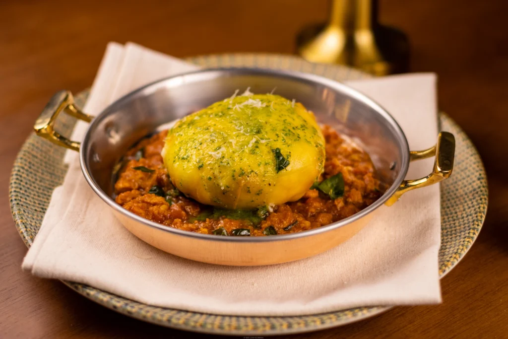 Prato servido em panela com preparo cremoso e acompanhamento dourado ao centro.